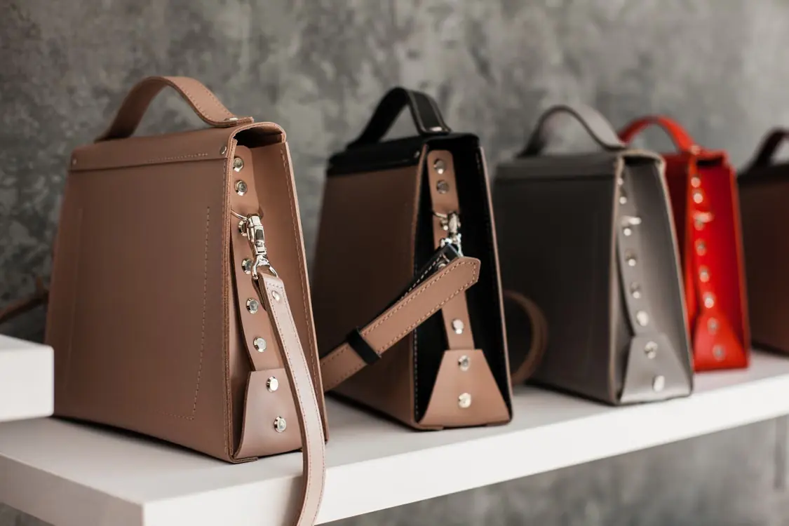 Leather bags arranged on a white wooden shelf
